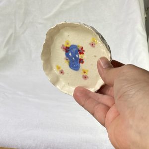 A hand holding the sugar skull ceramic dish.